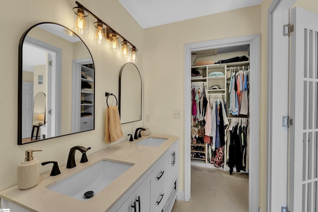 bathroom featuring marble finish floor, double vanity, a spacious closet, and a sink