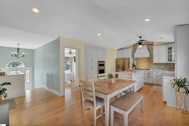 dining area featuring lofted ceiling, ceiling fan with notable chandelier, light wood-type flooring, and recessed lighting