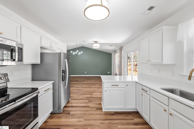 kitchen featuring a peninsula, a sink, visible vents, white cabinets, and appliances with stainless steel finishes