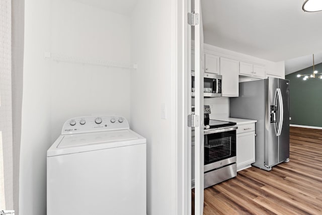 kitchen with stainless steel appliances, washer / clothes dryer, light countertops, white cabinetry, and wood finished floors