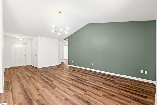 unfurnished living room with lofted ceiling, baseboards, a chandelier, and wood finished floors