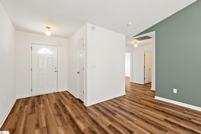 foyer featuring lofted ceiling, wood finished floors, visible vents, and baseboards