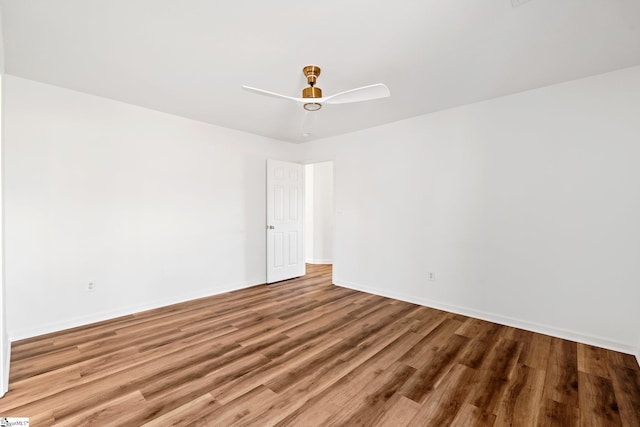 unfurnished room with wood finished floors, a ceiling fan, and baseboards