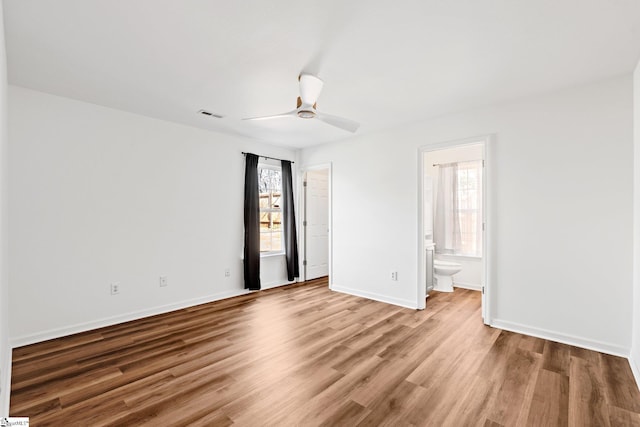 interior space with multiple windows, wood finished floors, visible vents, and baseboards