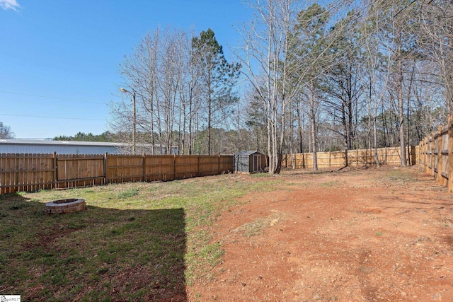 view of yard featuring a fire pit, a storage shed, an outbuilding, and a fenced backyard