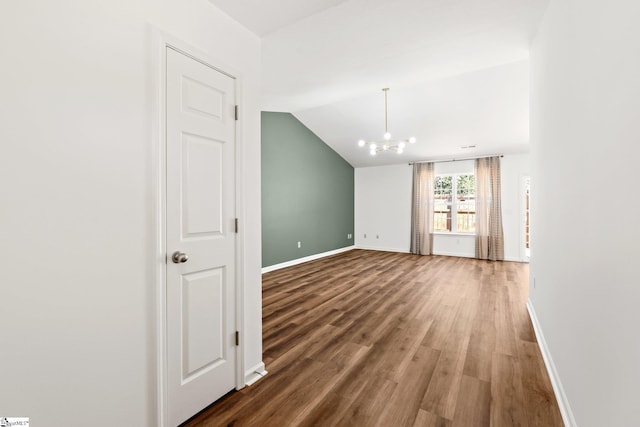 spare room featuring vaulted ceiling, wood finished floors, and baseboards