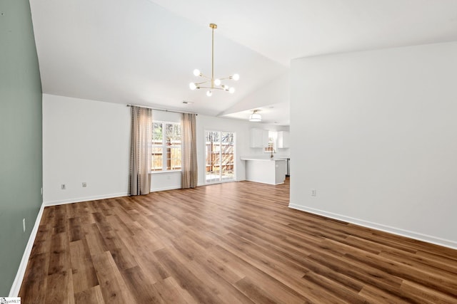 unfurnished living room with vaulted ceiling, baseboards, wood finished floors, and an inviting chandelier