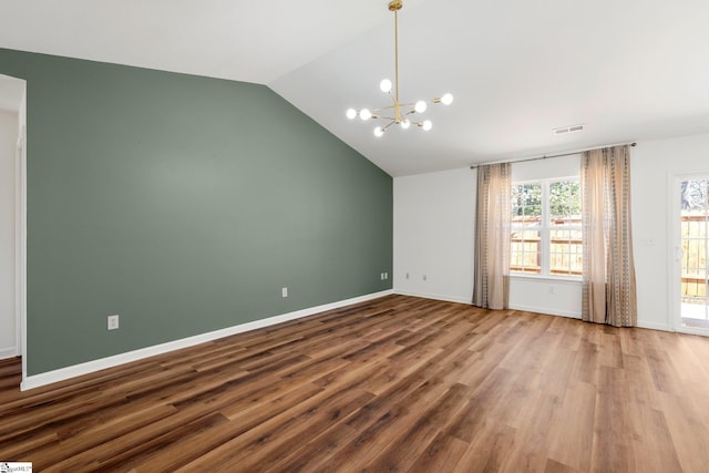 spare room featuring a notable chandelier, visible vents, vaulted ceiling, wood finished floors, and baseboards