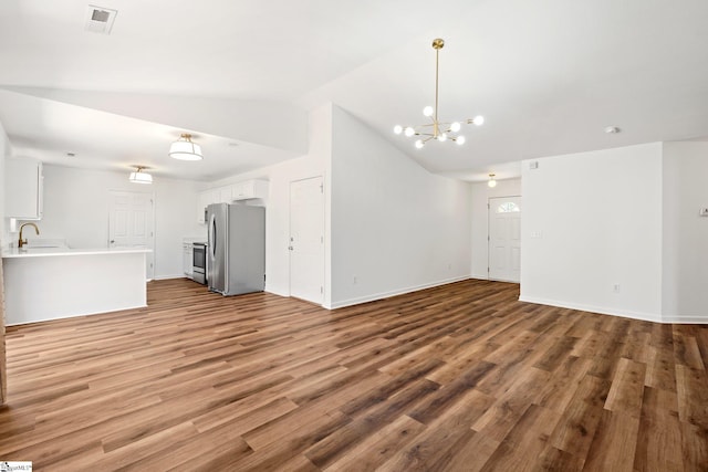 unfurnished living room with baseboards, visible vents, vaulted ceiling, and wood finished floors