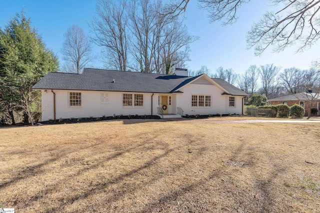 ranch-style home with a chimney and a front lawn