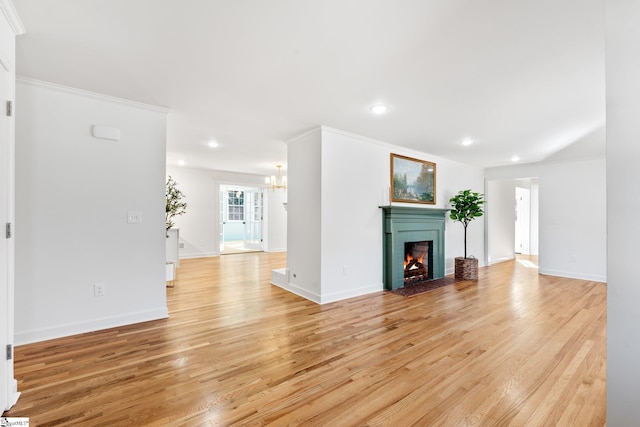 unfurnished living room with a warm lit fireplace, recessed lighting, light wood-style floors, and an inviting chandelier