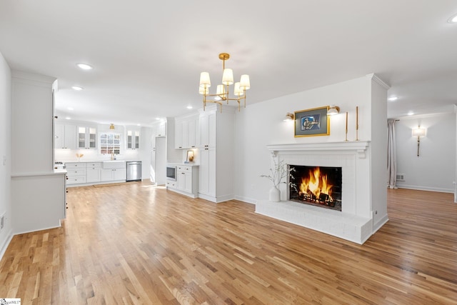 unfurnished living room featuring light wood-style floors, recessed lighting, a brick fireplace, and a sink