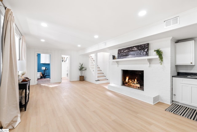 living room featuring visible vents, stairs, light wood-style floors, a fireplace, and recessed lighting