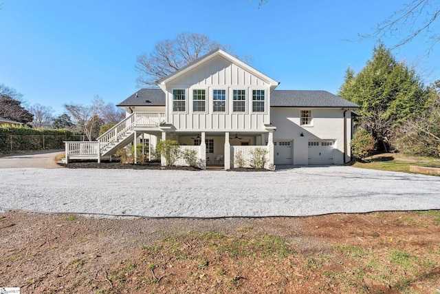 back of property with board and batten siding, ceiling fan, a garage, driveway, and stairs