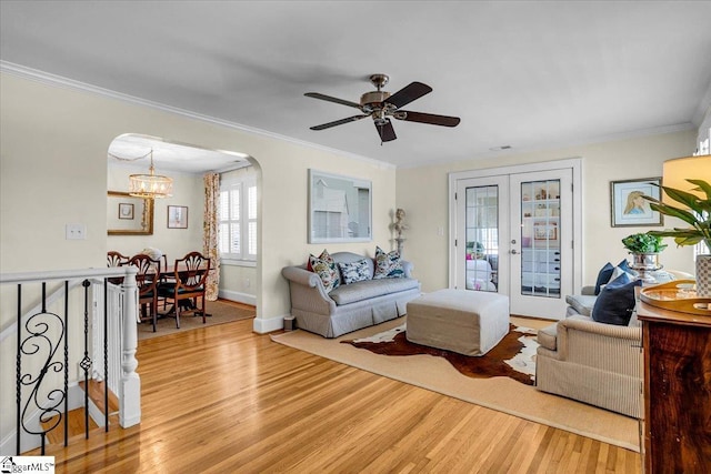 living area with arched walkways, ornamental molding, wood finished floors, and french doors