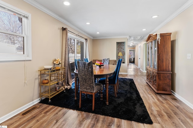 dining area featuring baseboards, visible vents, crown molding, and wood finished floors