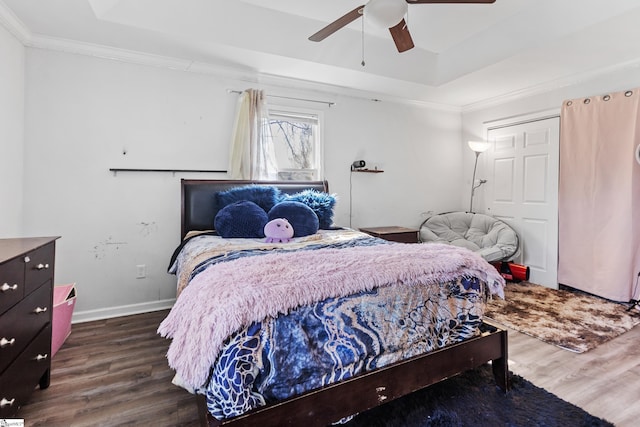 bedroom with ornamental molding, a tray ceiling, and wood finished floors