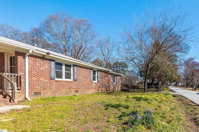 view of property exterior with crawl space, brick siding, and a yard