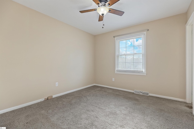 carpeted spare room with a ceiling fan, visible vents, and baseboards