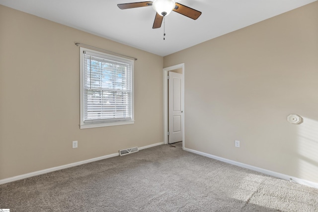 spare room with a ceiling fan, carpet flooring, visible vents, and baseboards