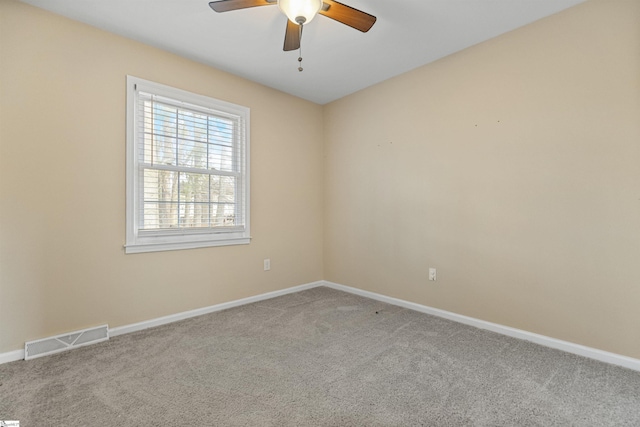 carpeted spare room with a ceiling fan, visible vents, and baseboards