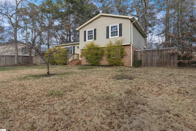 view of front of house featuring brick siding, a front yard, and fence