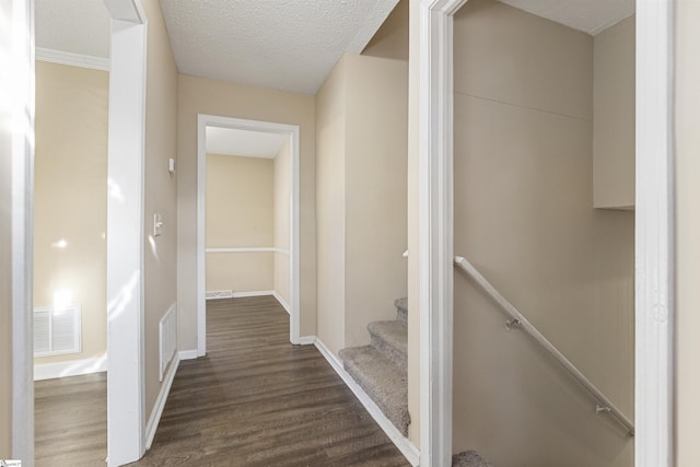 hall with baseboards, a textured ceiling, visible vents, and dark wood-type flooring