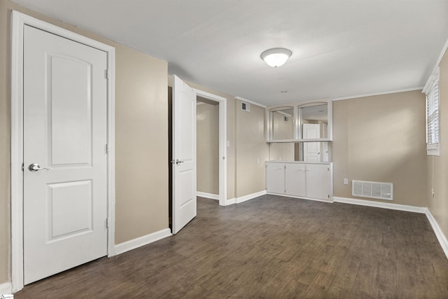 empty room featuring dark wood finished floors, visible vents, and baseboards