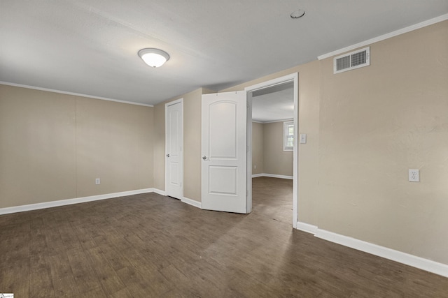 unfurnished bedroom with dark wood-style flooring, visible vents, crown molding, and baseboards