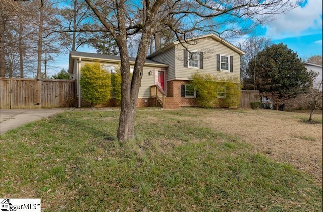 tri-level home with brick siding, a front lawn, and fence