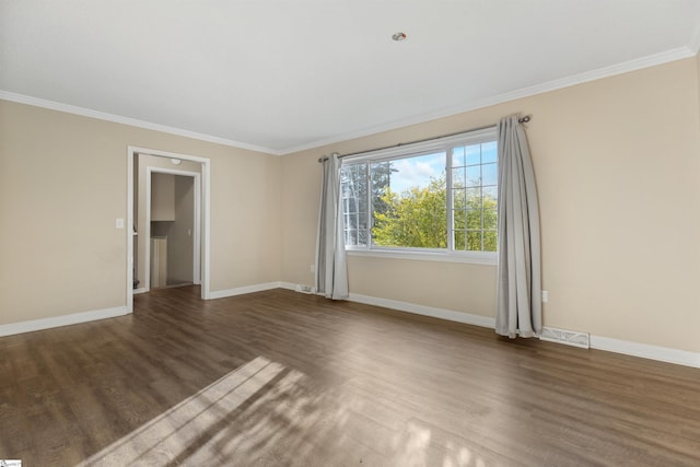 empty room with ornamental molding, wood finished floors, visible vents, and baseboards