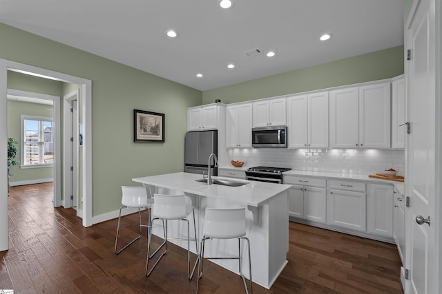 kitchen with dark wood-style flooring, a sink, visible vents, white cabinetry, and appliances with stainless steel finishes