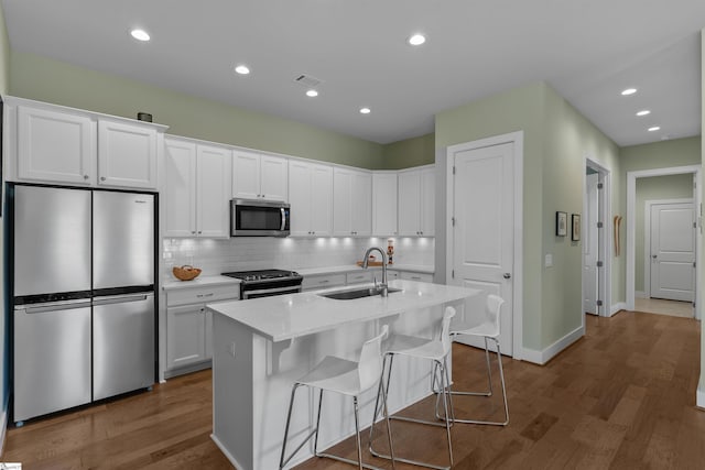 kitchen with visible vents, white cabinets, appliances with stainless steel finishes, a sink, and backsplash