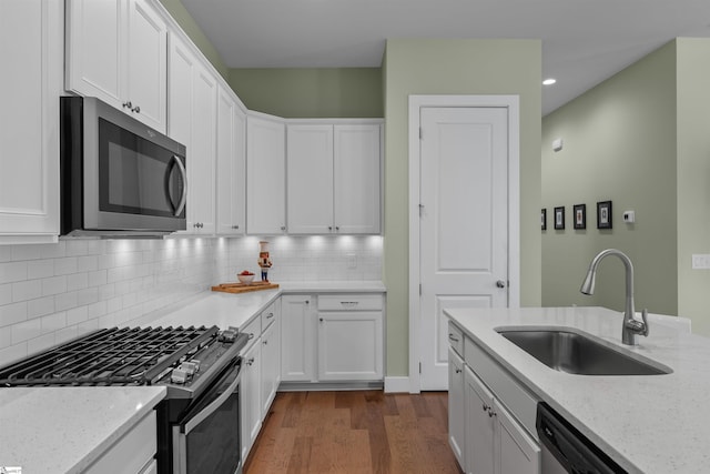 kitchen featuring appliances with stainless steel finishes, a sink, dark wood finished floors, and white cabinets