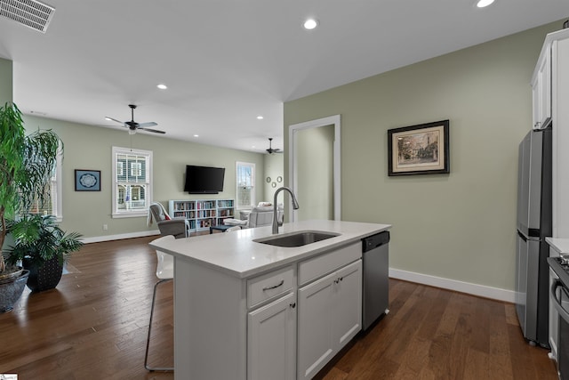 kitchen with dark wood finished floors, appliances with stainless steel finishes, open floor plan, light countertops, and a sink