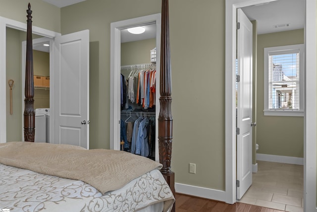 bedroom with a closet, a walk in closet, visible vents, and baseboards