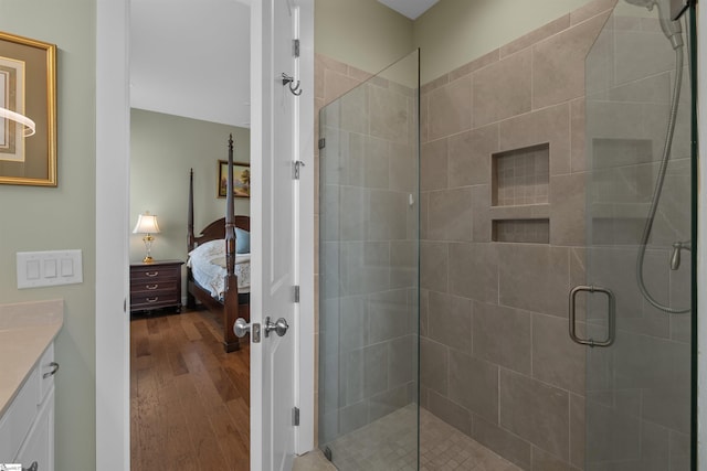 ensuite bathroom featuring wood finished floors, ensuite bath, vanity, and a shower stall