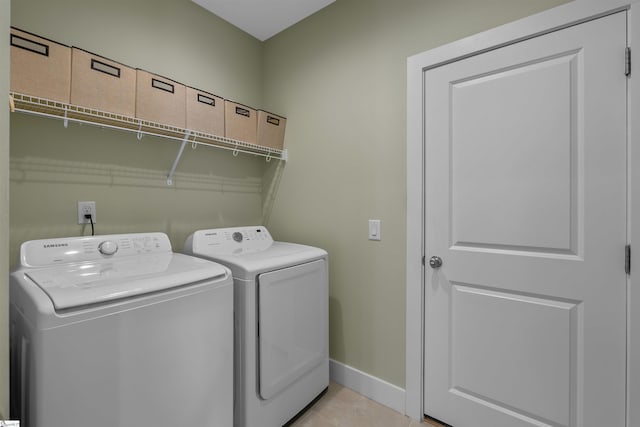 clothes washing area featuring laundry area, light tile patterned floors, baseboards, and washer and dryer