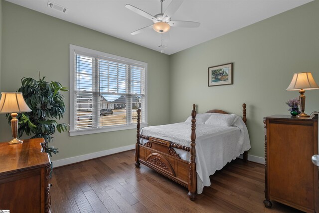 bedroom with baseboards, visible vents, dark wood finished floors, and a ceiling fan