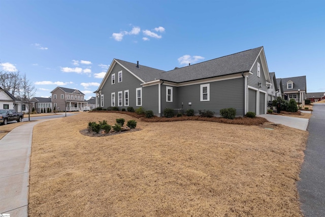 view of side of home with a garage, concrete driveway, and a residential view