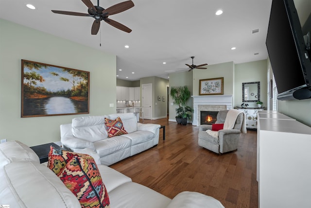 living room featuring recessed lighting, visible vents, ceiling fan, a stone fireplace, and wood finished floors