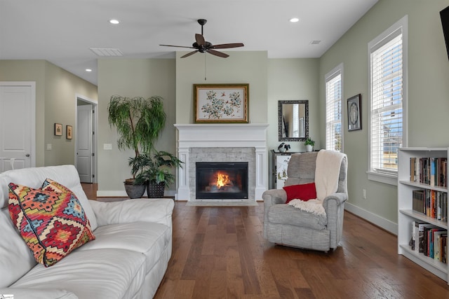 living room featuring recessed lighting, a stone fireplace, baseboards, and wood finished floors