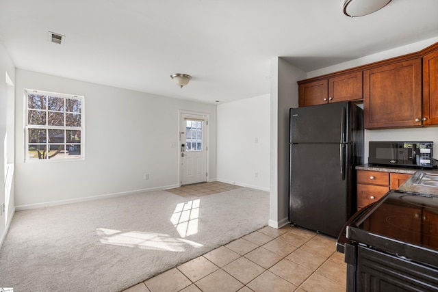 kitchen with light carpet, black appliances, brown cabinets, and baseboards