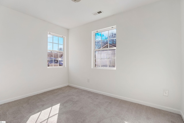 empty room featuring carpet floors, visible vents, and baseboards