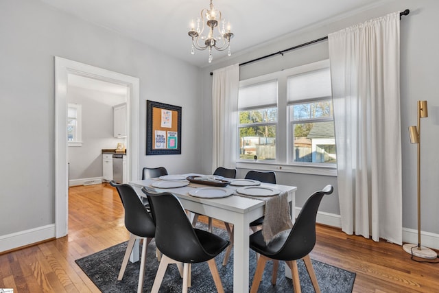 dining space with baseboards, a chandelier, and hardwood / wood-style floors