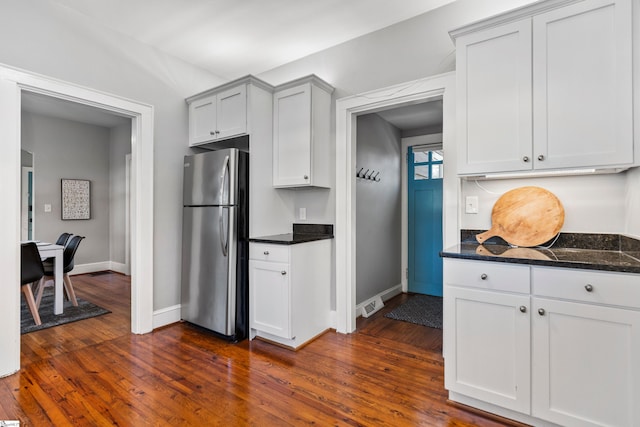 kitchen with dark stone counters, dark wood-style flooring, freestanding refrigerator, and baseboards