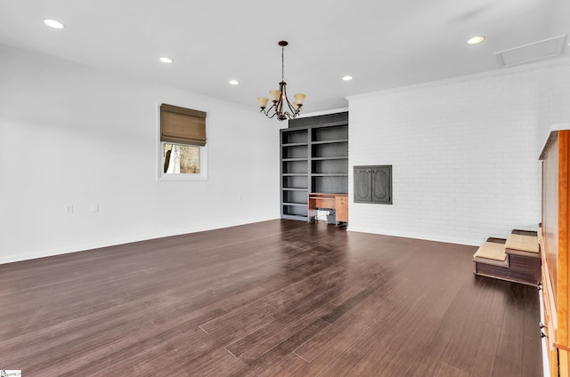 unfurnished living room with dark wood-style floors, crown molding, recessed lighting, brick wall, and a chandelier