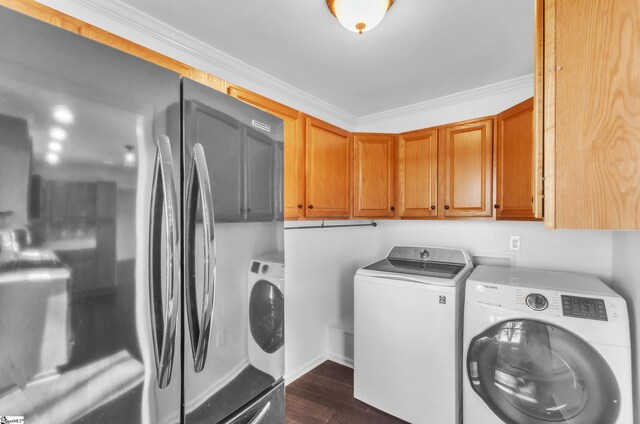 clothes washing area featuring ornamental molding, dark wood-style flooring, washing machine and clothes dryer, and cabinet space