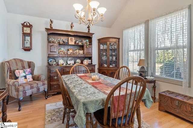 dining space featuring a chandelier, light wood-type flooring, and vaulted ceiling