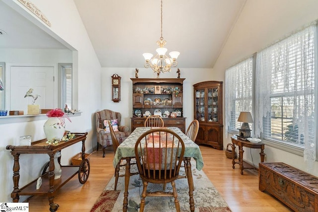 dining space with lofted ceiling, light wood-type flooring, and a notable chandelier